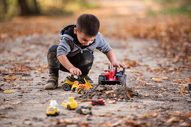 istock Child playing with toy trucks in autumn forest 2232192762