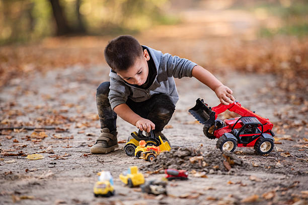 istock Child playing with toy trucks in autumn forest road 2232192776