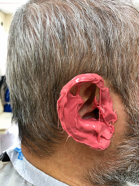 Close-up of a man’s ear covered with pink wax at a barber shop, a method used for removing unwanted ear hair during grooming.