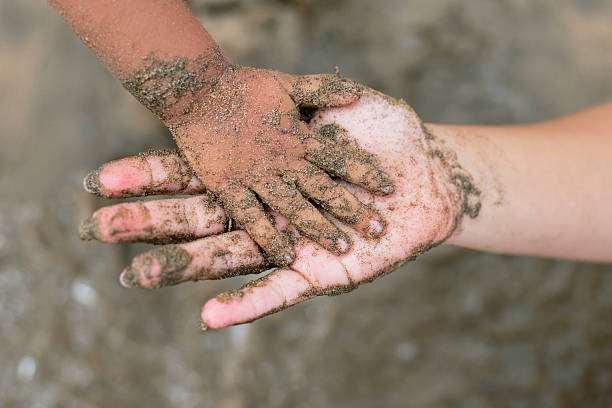istock Parent and child holding hands covered in sand on the beach 2232196581
