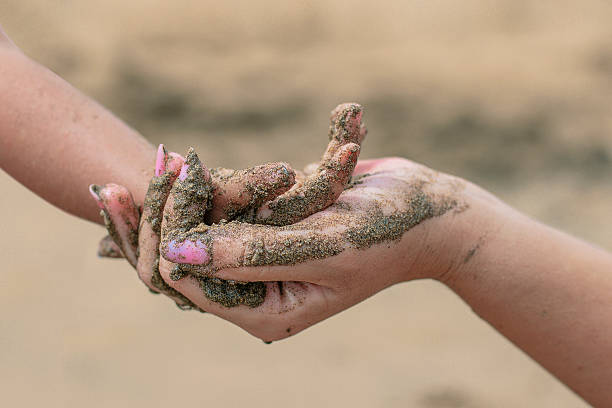 istock Mother and daughter holding hands covered in sand on beach 2232196617