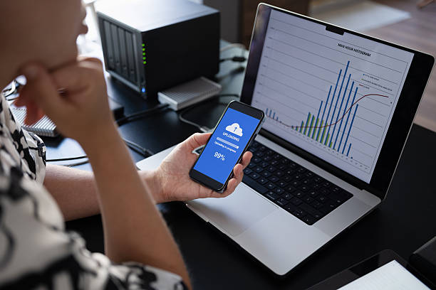 istock Woman uploading files to cloud using her smart phone 2232196630