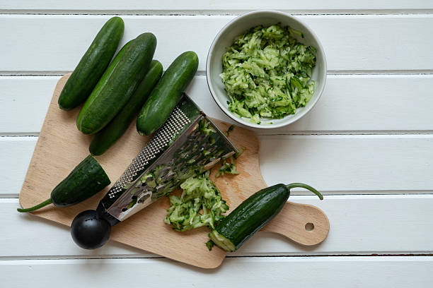 Grated and whole cucumber on cutting board