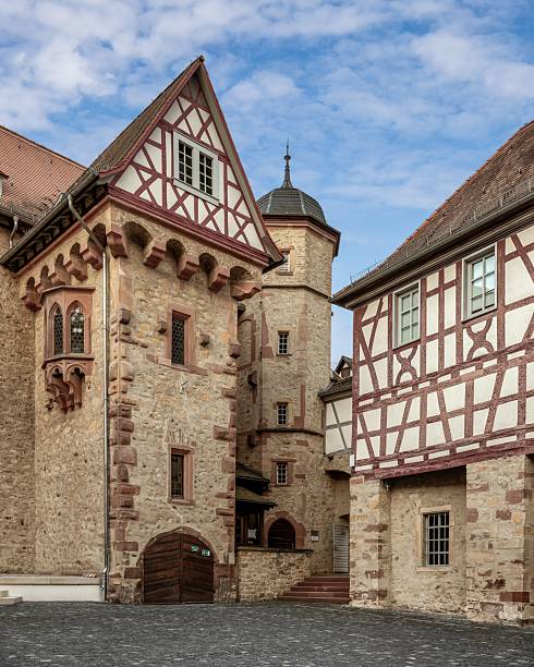 Medieval architecture of a historic building with timber framing and stone walls under a partly cloudy sky in Heppenheim, Germany.