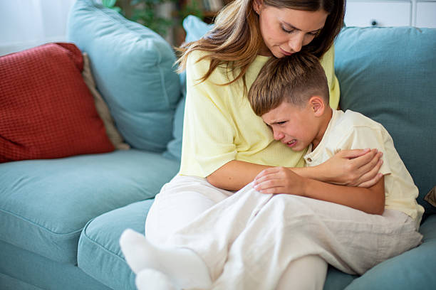 istock Mother comforting her crying son on the sofa at home 2232203290