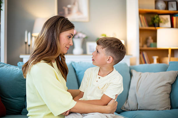 istock Mother embracing and talking to son at home on sofa 2232203605