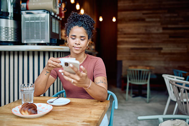 istock Young woman enjoying coffee and using smartphone in cafe 2232204618