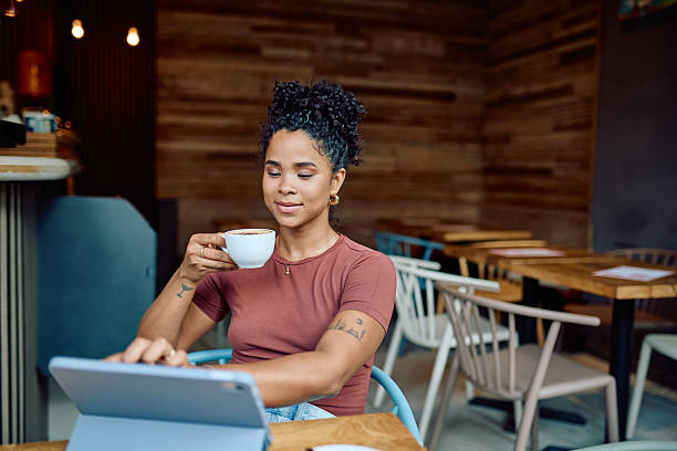 istock Young woman drinking coffee and using digital tablet in cafe 2232204688