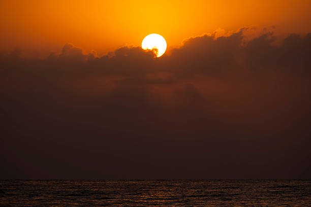 istock Morning sun rising through clouds over water. 2232205437