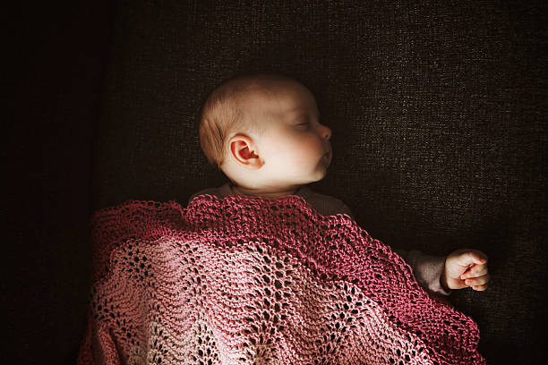 A high angle shot of an adorable baby girl, 3 months old, sleeping on a couch. Shot with a Canon 5D Mark IV.