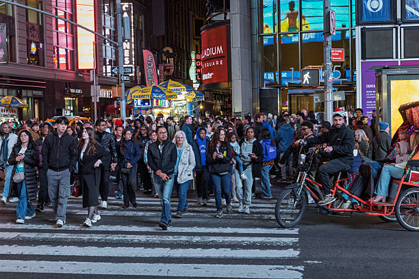 A crowd of people begins to cross Broadway in Times Square New York City