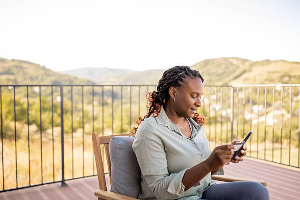 istock African woman sitting on patio using smart phone for online purchase 2232216000