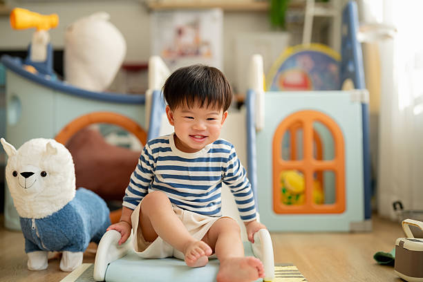 istock Happy Asian toddler boy laughs joyfully while playing on plastic slide toy, demonstrating gross motor development and emotional regulation through active play exploration and sensorimotor learning experiences 2232218201