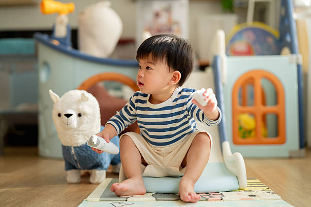 istock Happy Asian toddler boy laughs joyfully while playing on plastic slide toy, demonstrating gross motor development and emotional regulation through active play exploration and sensorimotor learning experiences 2232218208