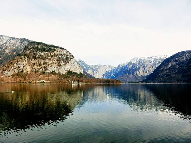 This peaceful image showcases a calm mountain lake surrounded by towering peaks, with the water perfectly reflecting the surrounding landscape and sky. The tranquil setting and pristine natural beauty make it ideal for themes of outdoor adventure, nature retreats, environmental serenity, and scenic travel. Perfect for editorial use, wellness content, tourism campaigns, and inspirational visuals.