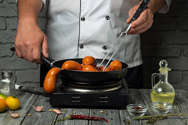 istock A chef skillfully flips sausages in a frying pan on a stove. Surrounding ingredients include garlic, herbs, and spices, creating a welcoming atmosphere 2232222188