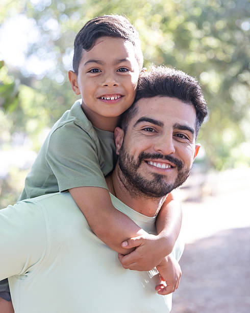 istock Father giving son a piggy back ride in a park 2232224111