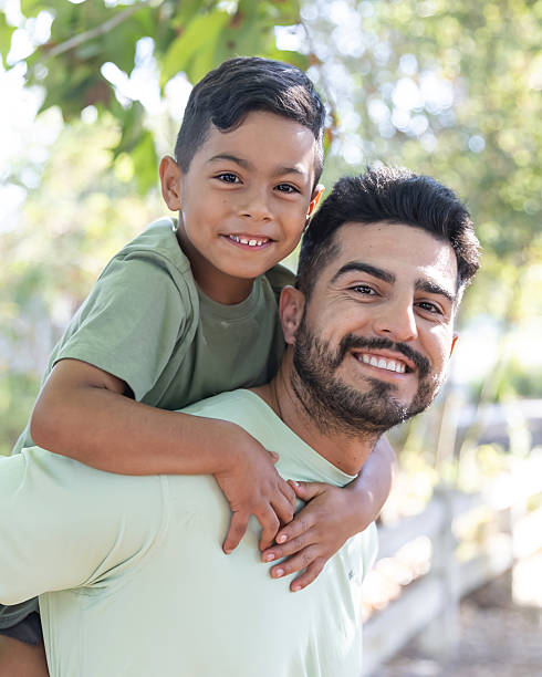 istock Father giving son a piggy back ride in a park 2232224120