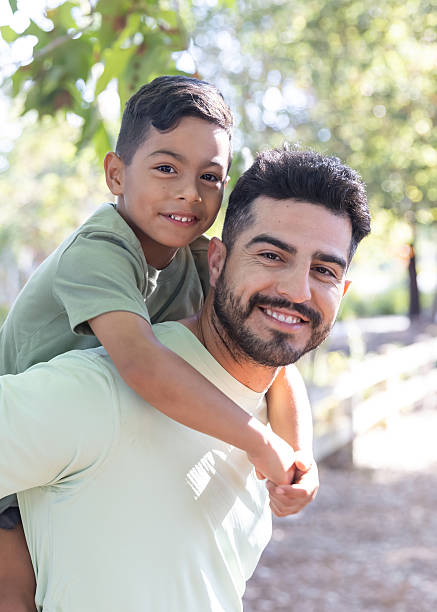 istock Father giving son a piggy back ride in a park 2232224122