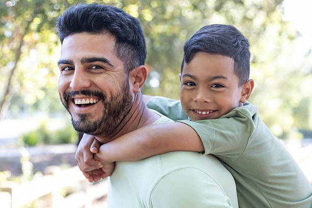 istock Father giving son a piggy back ride in a park 2232224139