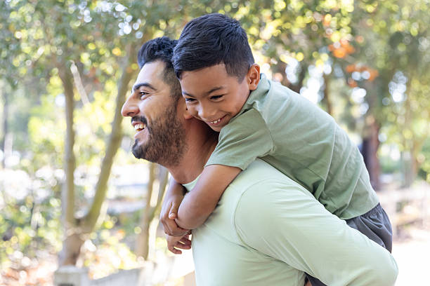 istock Father giving son a piggy back ride in a park 2232224168