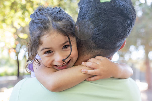 Father holding daughter and she is looking at camera over shoulder