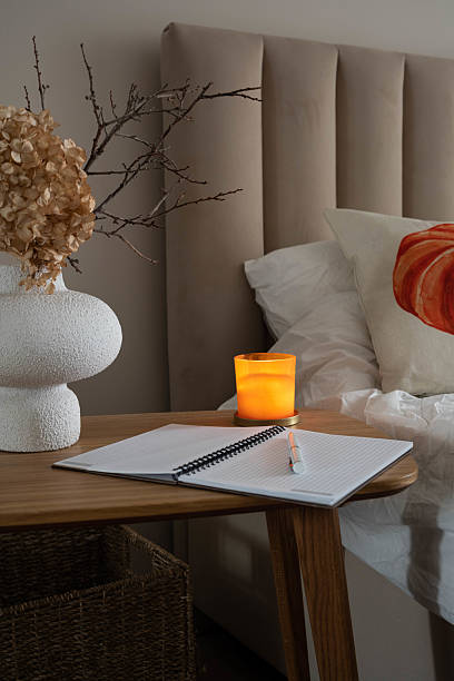 istock A serene bedside setup with a glowing candle, elegant vase, and comforting open notebooks creates a autumn cozy ambiance. 2232228739