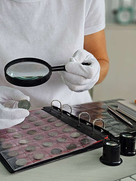 istock Coin collector examines valuable coins with magnifying glass 2232232451