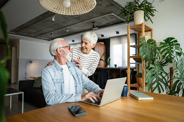 istock Senior couple using laptop at home smiling and interacting 2232233320