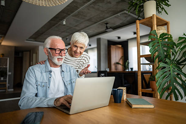 Happy senior couple using laptop at home