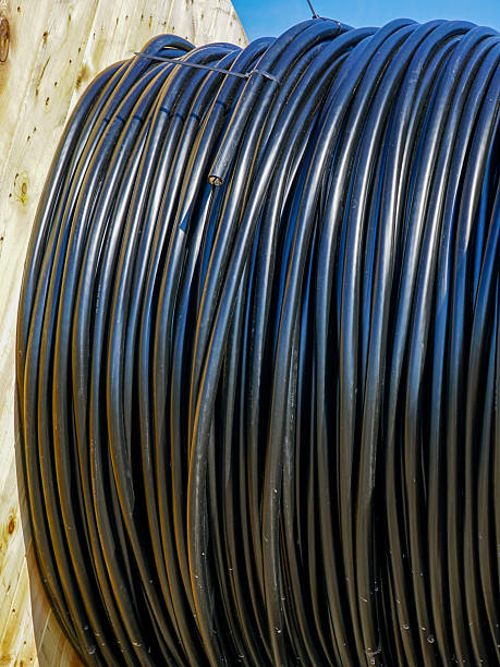 istock Large black cable coil on wooden spool used for construction and power installation against blue sky 2232233753