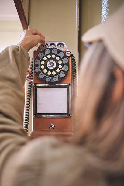 istock Woman dialing a rotary phone hanging on the wall 2232234814