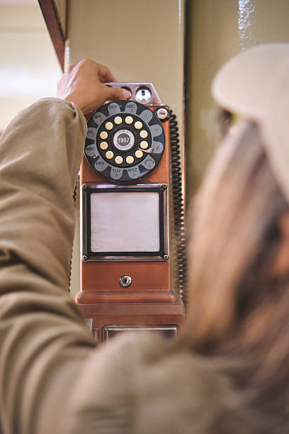 istock Woman dialing a rotary phone hanging on the wall 2232234816