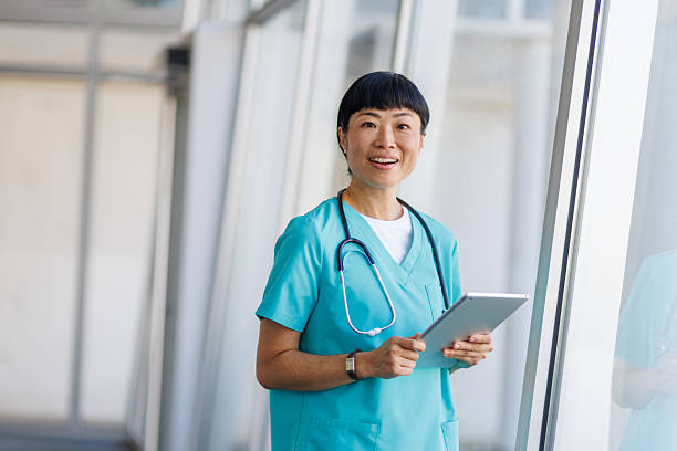 istock Smiling asian doctor using digital tablet in hospital corridor 2232241940