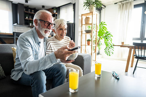 istock Happy senior couple watching television and eating popcorn on sofa 2232249821