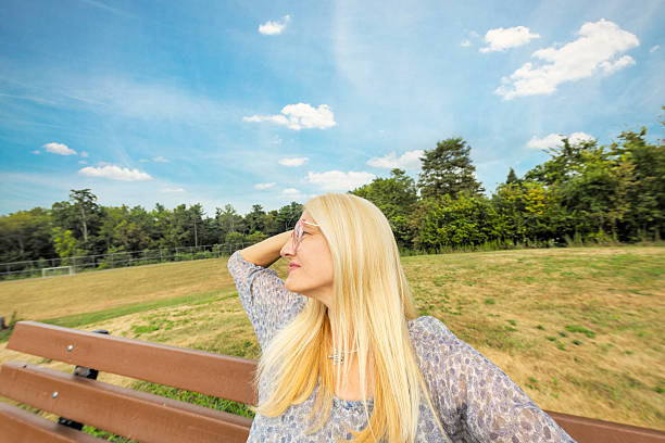Young happy woman wearing blue dress and hat on the bridge near sea, summer time.