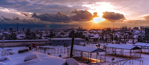 istock Snowy cityscape at sunset with dramatic clouds and warm light 2232255585