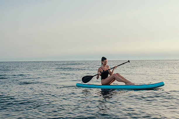 istock Young woman relaxing on a stand up paddle board at sunset 2232256802