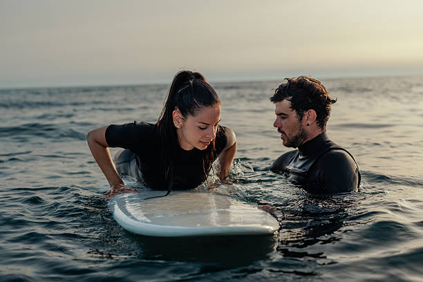 istock Surfing instructor teaching beginner surfer how to paddle on a surfboard 2232256803