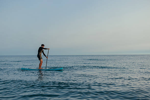 istock Young man paddling on a stand up paddle board at dawn 2232256807