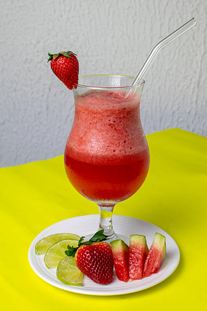 Healthy detox berry smoothie with fresh ingredients such as strawberry, watermelon, and lemon, a refreshing vegan drink for a healthy lifestyle and diet, served in a glass on a bright yellow table.