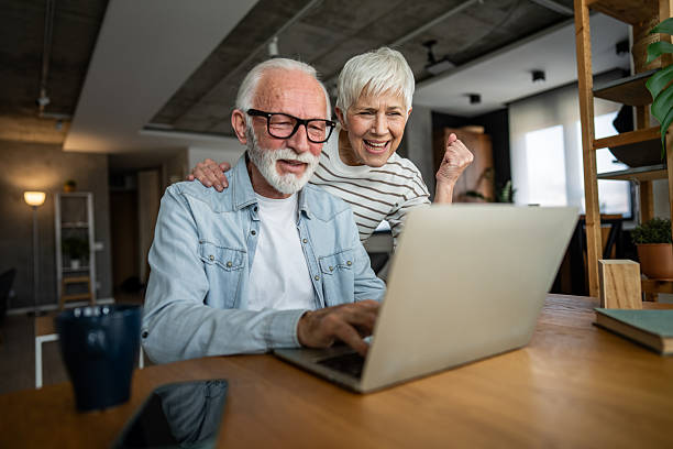 istock Excited senior couple celebrating success while using laptop at home 2232262037