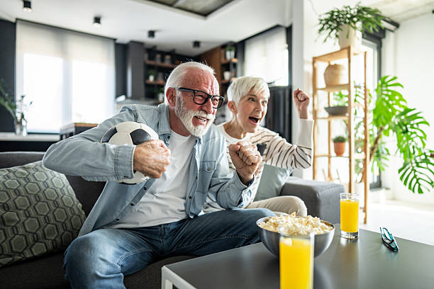 istock Excited senior couple cheering while watching soccer match on tv 2232267134