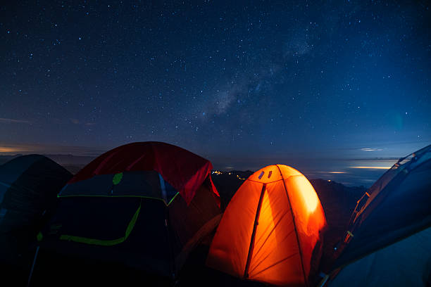 istock Orange camping tent illuminated inside during a blue starry night 2232268027