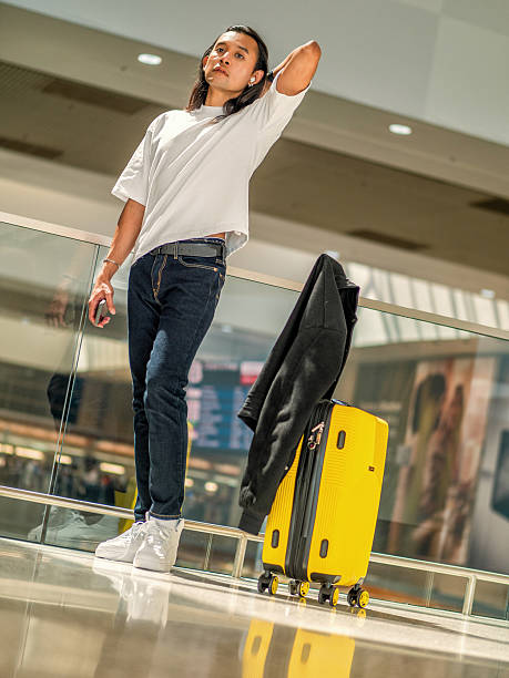 istock Asian man with yellow suitcase in airport terminal 2232269430