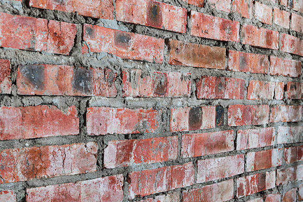 Close-up of an old red brick wall with rough mortar. Rustic and weathered texture suitable for construction themes, industrial design