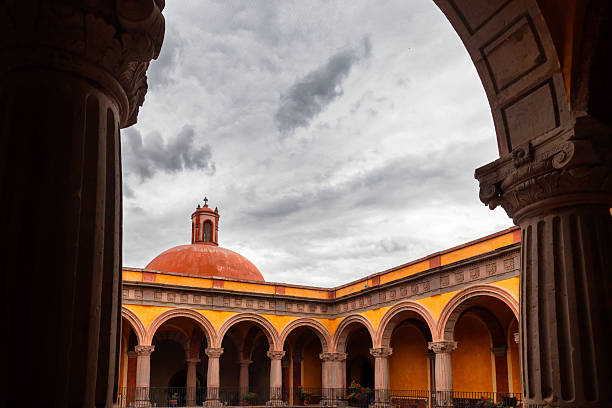 Architectural structure with red dome, carved columns and arched galleries in former monastery in Queretaro, Mexico