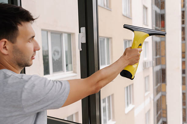istock Back view of professional cleaning service worker washing windows in high-rise building using cordless electric window wiper ensuring streak-free 2232275885