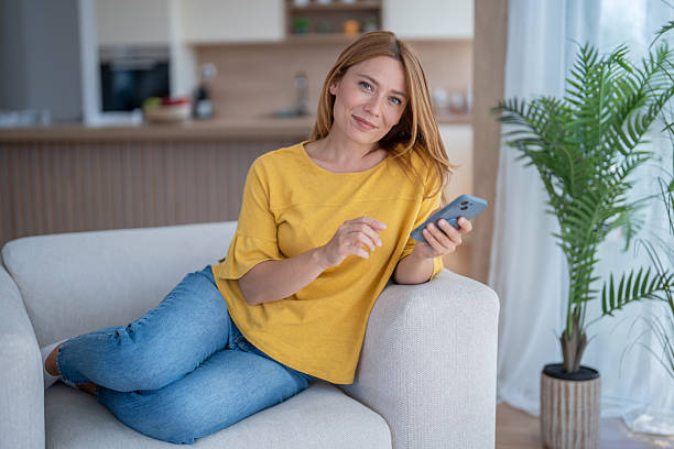 istock Woman relaxing on sofa using smartphone at home 2232276058