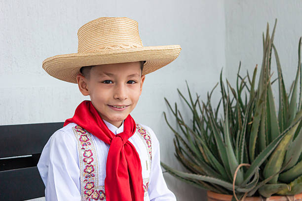 Portrait of a Latin American boy outdoors at a farm wearing a ruana and looking at the camera smiling â lifestyle in Developing Countries concepts